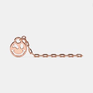 May include: A gold chain necklace with a winking smiley face charm.