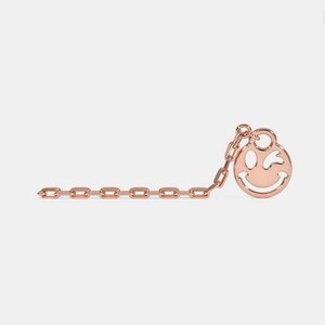 May include: A rose gold chain necklace with a winking smiley face charm.