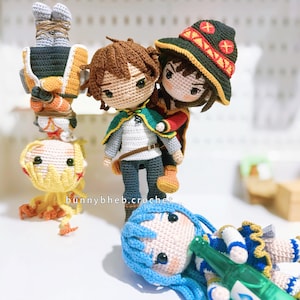 以下が含まれることがあります： アニメキャラクターをモチーフにした手作りの編みぐるみ人形4体。逆さまの人形、緑のマントを羽織った人形、赤のアクセントがある濃い緑の帽子を被った人形、そして緑のボトルを持った青い髪の人形が横たわっています。テキストはbunnybheb.crochetと書かれています。