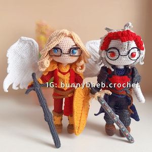 May include: Two handmade crochet dolls featuring intricate details. The left doll has blonde hair, white wings, and red and gold armor, holding a dark sword and shield. The right doll has grey hair, red accents, and dark armor, holding a sword. Text reads: IG: bunnybheb.crochet