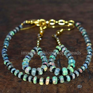 May include: A set of opal and black gemstone bead necklaces and earrings. The necklaces are made with alternating black and iridescent white opal beads. The earrings are made with iridescent white opal beads.