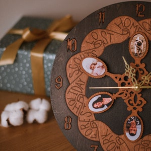 Puede incluir: Un reloj de madera marrón oscuro con un diseño único. La esfera del reloj presenta un diseño circular con un patrón de cinta que dice "Today's Go To's" y "Forever Yours". El reloj tiene una manecilla de reloj dorada y una esfera negra con números romanos. Hay cuatro marcos de fotos ovalados con fotos de personas y un perro.