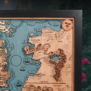 May include: A framed, layered wooden map with a black border. The map features a blue ocean and light brown landmasses with the text "FAERIE REALMS". Ships, trees, and other details are carved into the wood. The map is a decorative piece.