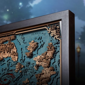May include: A framed wooden map of a fantasy world, featuring detailed landmasses in a light brown hue against a teal background. The map is labeled "Azeroth" and "The North Sea". The frame is black with decorative corner accents.