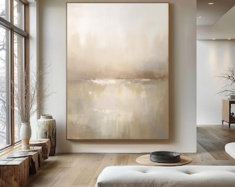 May include: Large abstract painting in neutral tones of beige, cream, and brown. The artwork is framed in a simple wooden frame and hangs on a white wall. The painting evokes a sense of calm and serenity, suitable for home decor.