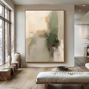 May include: Abstract painting featuring shades of beige, green, and gold. The artwork is displayed on a wall in a contemporary living room.