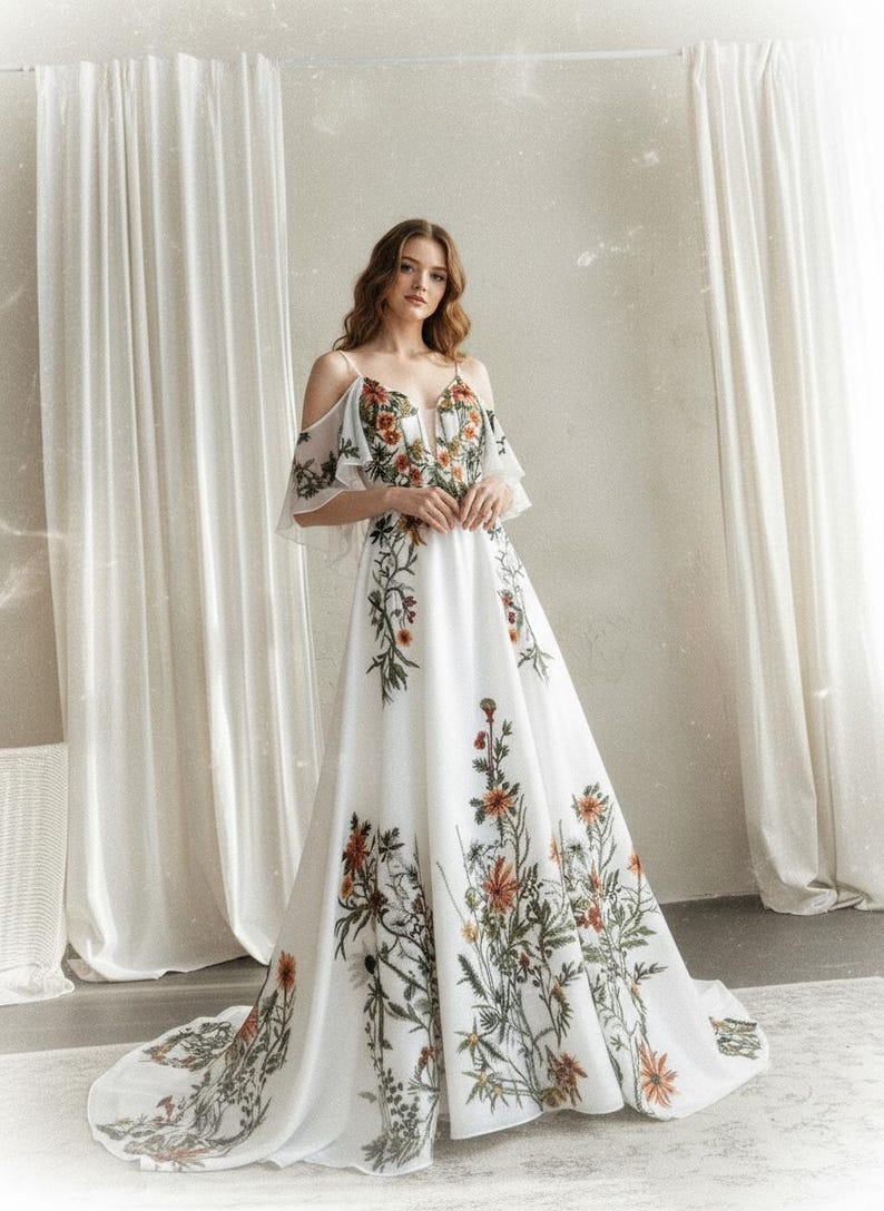 May include: A white floral print gown with a plunging neckline and cold shoulder sleeves. The dress features a flowing skirt and is adorned with a botanical design in shades of orange, green, and brown. The gown is suitable for a wedding or special occasion.