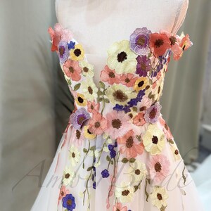 May include: A white off-the-shoulder dress with a floral embroidery design. The embroidery features a variety of colors, including pink, yellow, purple, and blue.