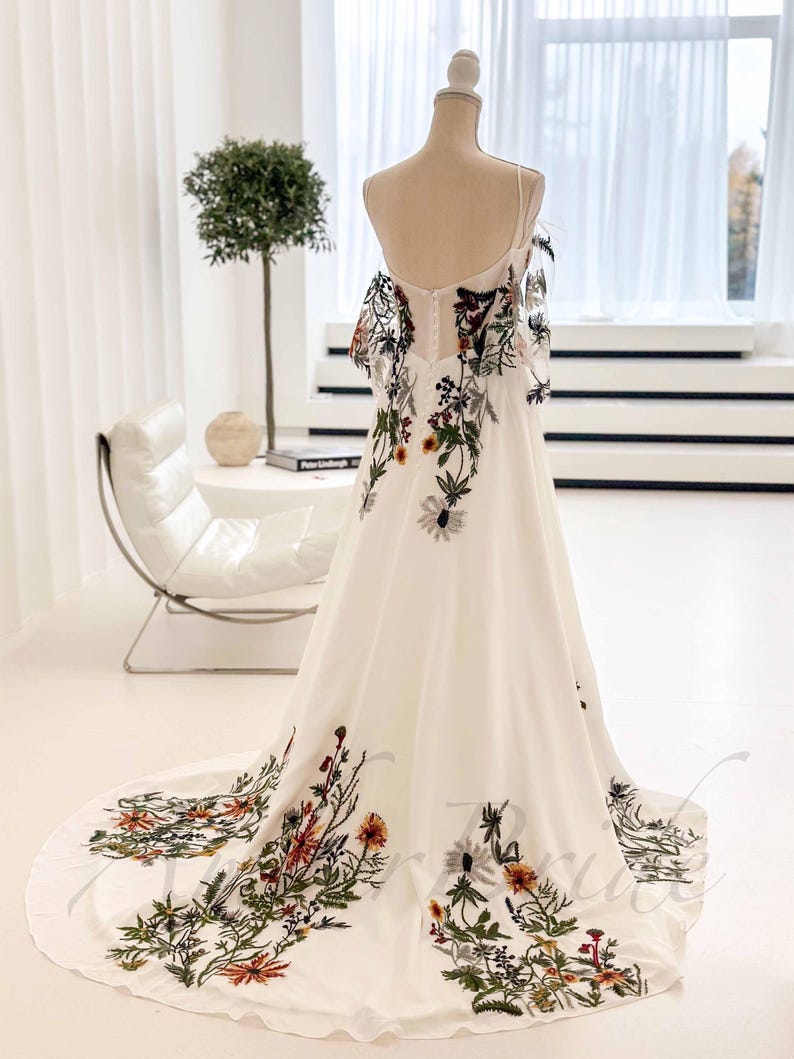 May include: A white maxi dress with a floral print. The dress has a fitted bodice and a flowing skirt. The floral print is in shades of green, orange, and brown.