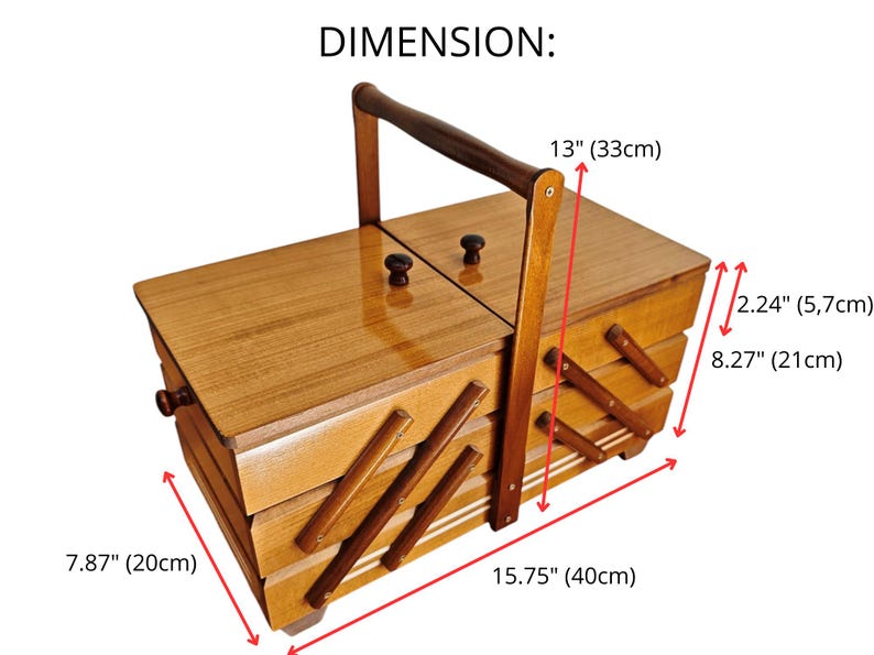 Pu&ograve; includere: Un portacucito in legno con design a sbalzo a pi&ugrave; livelli, dotato di una maniglia centrale e due coperchi superiori con piccoli pomelli. La scatola misura 40 cm di lunghezza, 20 cm di larghezza e 21 cm di altezza, con livelli alti 5,7 cm.