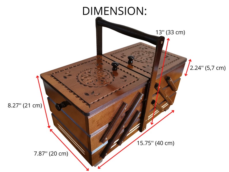 Puede incluir: Una caja de costura de madera con tapa abatible y asa. La caja tiene un dise&ntilde;o tallado en la parte superior y est&aacute; dividida en compartimentos. La caja mide 33 cm de alto, 40 cm de ancho y 21 cm de profundidad.