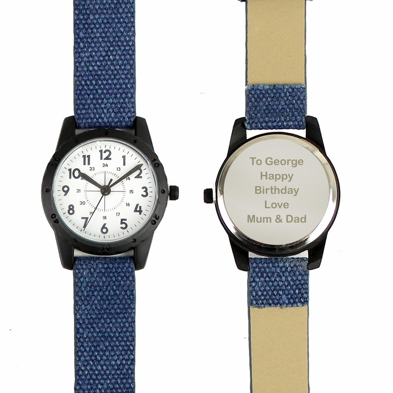 May include: A black wristwatch with a white face and blue canvas band. The watch face displays black numerals and hands. The back of the watch has the inscription "To George Happy Birthday Love Mum & Dad."