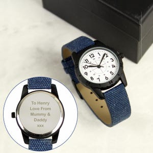 May include: Black wristwatch with a white face and black numerals. The watch has a blue fabric band and a black case. The back of the watch is engraved with the text "To Henry Love From Mummy & Daddy XXX".