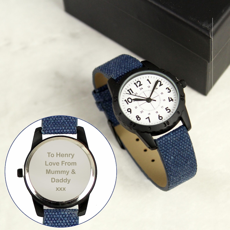 May include: Black wristwatch with a white face and black numerals. The watch has a blue fabric band and a black case. The back of the watch is engraved with the text "To Henry Love From Mummy & Daddy XXX".