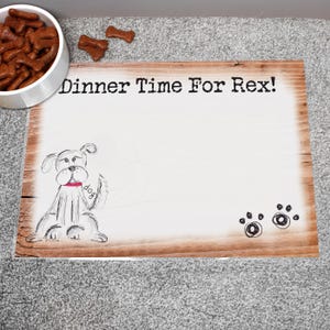 May include: Wooden dog-themed placemat with the text "Dinner Time For Rex!" and a sketched dog illustration. Includes paw prints and a bowl of dog biscuits. The placemat has a light wood grain.