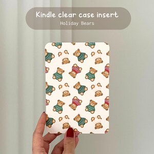 May include: A Kindle clear case insert featuring a repeating pattern of brown teddy bears in green and red sweaters and white chef hats. The text "Kindle clear case insert" and "Holiday Bears" are at the top.