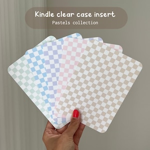 May include: Five checkered patterned paper inserts in pastel colours for a Kindle clear case. The colours are light blue, lavender, pink, beige, and light green.