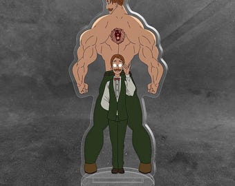 Könnte beinhalten: Ein transparenter Acryl-Aufsteller mit einer zweischichtigen Charakter-Illustration. Im Hintergrund ist eine große, muskulöse Figur mit einem Löwen-Tattoo auf dem Rücken zu sehen, während im Vordergrund eine kleinere Figur in Weste steht.