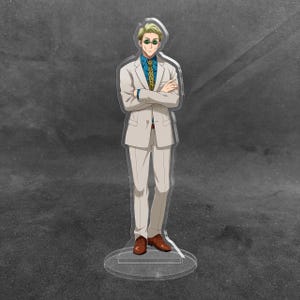 May include: An acrylic standee featuring a blonde character with round green sunglasses, wearing a beige suit, a blue collared shirt, and a yellow patterned tie. The character stands with arms crossed, wearing brown dress shoes on a clear base.