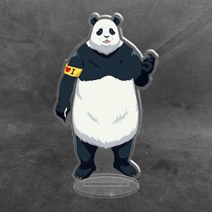 May include: An acrylic standee featuring a standing panda character with black and white fur, a smiling expression, and a yellow armband on its right arm that displays a red heart symbol followed by the letter I in black text.