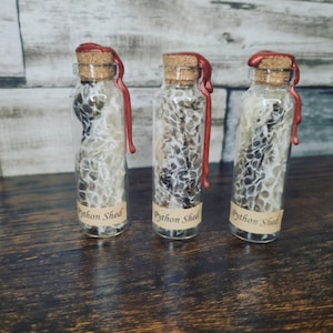 May include: Three small glass bottles with red wax seals and labels that say "Python Shed". Each bottle contains a shed snake skin.