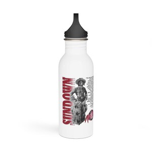 Op de afbeelding: Een witte waterfles van roestvrij staal met een zwarte dop. De fles heeft een rode en witte afbeelding van een vrouw die een wild paard berijdt met de tekst "SUNDOWN" verticaal aan de zijkant gedrukt. De tekst "The big boys got a new name for the rodeo..." is in zwart aan de zijkant van de fles gedrukt.