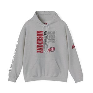 May include: A heather grey hooded sweatshirt featuring a black and white graphic of a bodybuilder, the text ANDERSON, and a quote. The front includes a kangaroo pocket and white drawstrings. The sleeve features the text allstars.com.