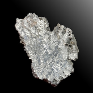 Könnte beinhalten: Ein rohes, metallisch silberfarbenes Mineralexemplar mit einer gezackten, unregelmäßigen Form. Die Oberfläche weist eine kristalline, poröse Textur mit verschiedenen Grautönen und hellen, reflektierenden metallischen Glanzlichtern auf.