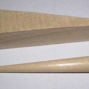 May include: Two wooden pieces for woodworking projects. A large, light brown wedge and a smaller, light brown tapered dowel.