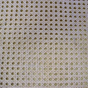 May include: Close-up of a woven cane material with a repeating pattern of small, evenly spaced holes. The natural, light beige color of the cane creates a textured surface, ideal for furniture or decorative projects.