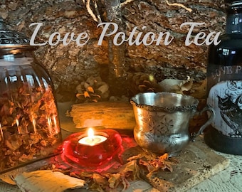 May include: A glass jar filled with dried rose petals, a silver cup, a red heart-shaped candle holder with a lit candle, and a black bottle with a label that reads "Love Potion" on a wooden surface. The text "Love Potion Tea" is written in white on a brown wooden background.