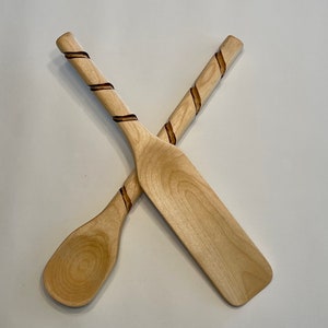 May include: Two wooden kitchen utensils with a spiral design carved into the handles. The utensils are a spoon and a spatula.