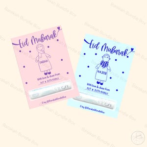 May include: Two pink and blue Eid Mubarak cards featuring a cartoon girl and boy in traditional clothing. The cards are personalised with the names "Fariha" and "Najeeb". The text "With love & duas from SUT & SUTO-KHALU" is included on both cards. The cards are decorated with small dots and hearts.