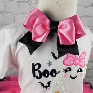 May include: A white t-shirt with a pink and black bow, embroidered with a ghost, stars, bats, and the word "Boo".