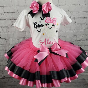 May include: Pink and black tutu with a white shirt featuring a ghost with the text "Boo" and the name "Alexis".