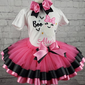 May include: A pink and black tutu with a white shirt featuring a ghost with a pink bow and the text "Boo" and "Alexis".