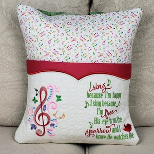 May include: A white pillow with a red pocket and a musical note design. The pillow has a green border and the text "I sing because I'm happy I sing because I'm free His eye is on the sparrow and I know He watches me".