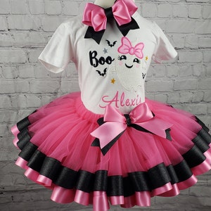 May include: A pink and black tutu with a white shirt featuring a ghost with the text "Boo" and the name "Alexis".
