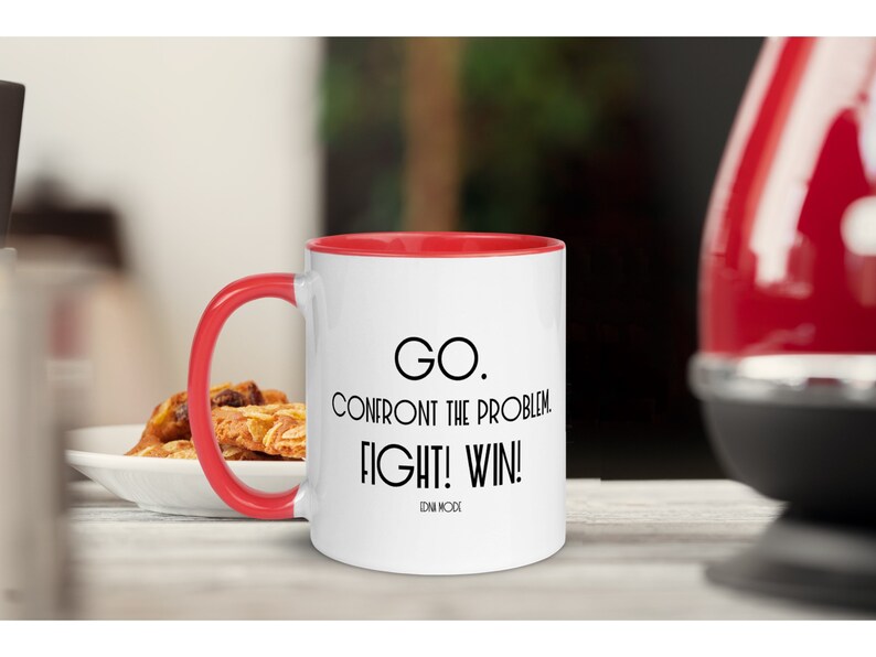 May include: White ceramic coffee mug with a red rim. The mug has a black quote that reads "GO. CONFRONT THE PROBLEM. FIGHT! WIN!" with the name "DAN WOOD" at the bottom.