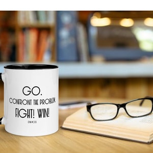 May include: White coffee mug with a black rim and handle. The mug has black text that reads "GO. CONFRONT THE PROBLEM FIGHT! WIN! EDNA MODE".