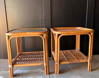 Un par de mesitas de noche de ratán con estante inferior y tapa de cristal.