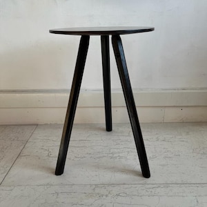 May include: A black wooden side table with a round top and three legs.