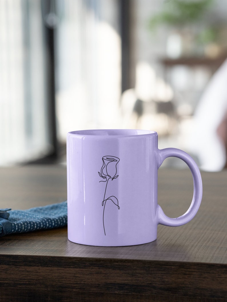 May include: A lavender ceramic mug with a single line drawing of a rose on the front.
