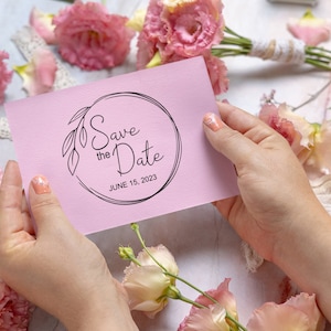 May include: A pink save the date card with a black circle and the text "Save the Date" and "JUNE 15, 2023".