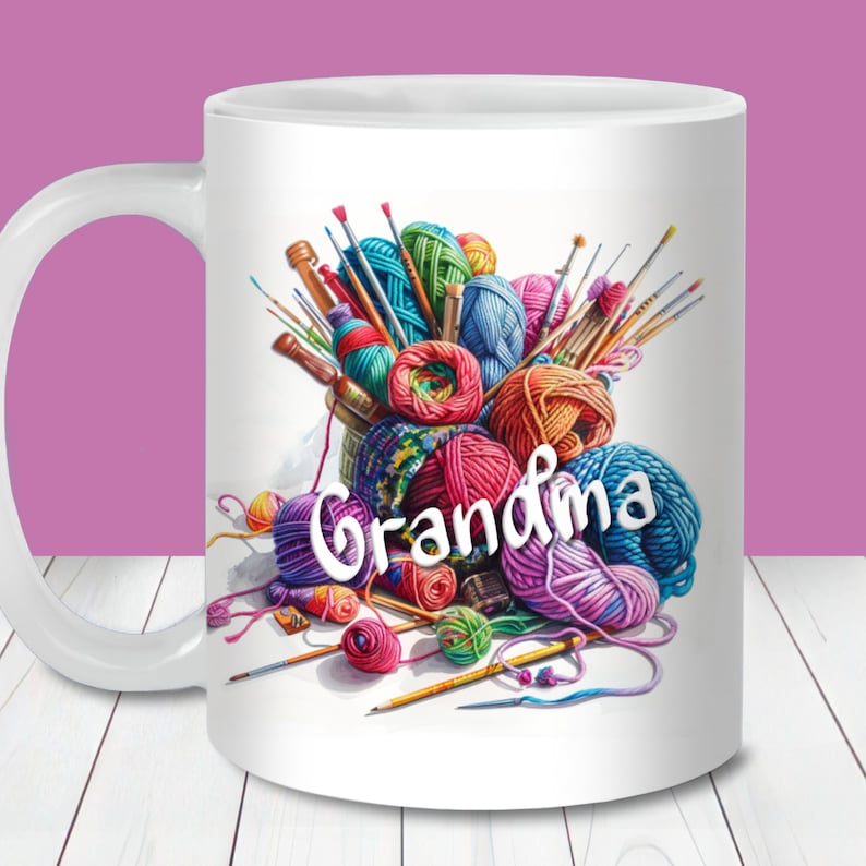 May include: White ceramic mug with a colourful illustration of yarn balls, knitting needles, and paintbrushes. The word "grandma" is written across the front in white. The mug has a white handle and is set against a white background.
