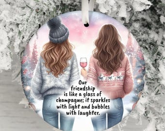 May include: Round Christmas ornament featuring two women in sweaters, one holding a wine glass. The ornament has the text: "Our friendship is like a glass of champagne; it sparkles with light and bubbles with laughter."