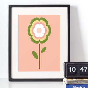 May include: A framed print of a stylised flower with green, yellow, pink and white petals on a peach background.