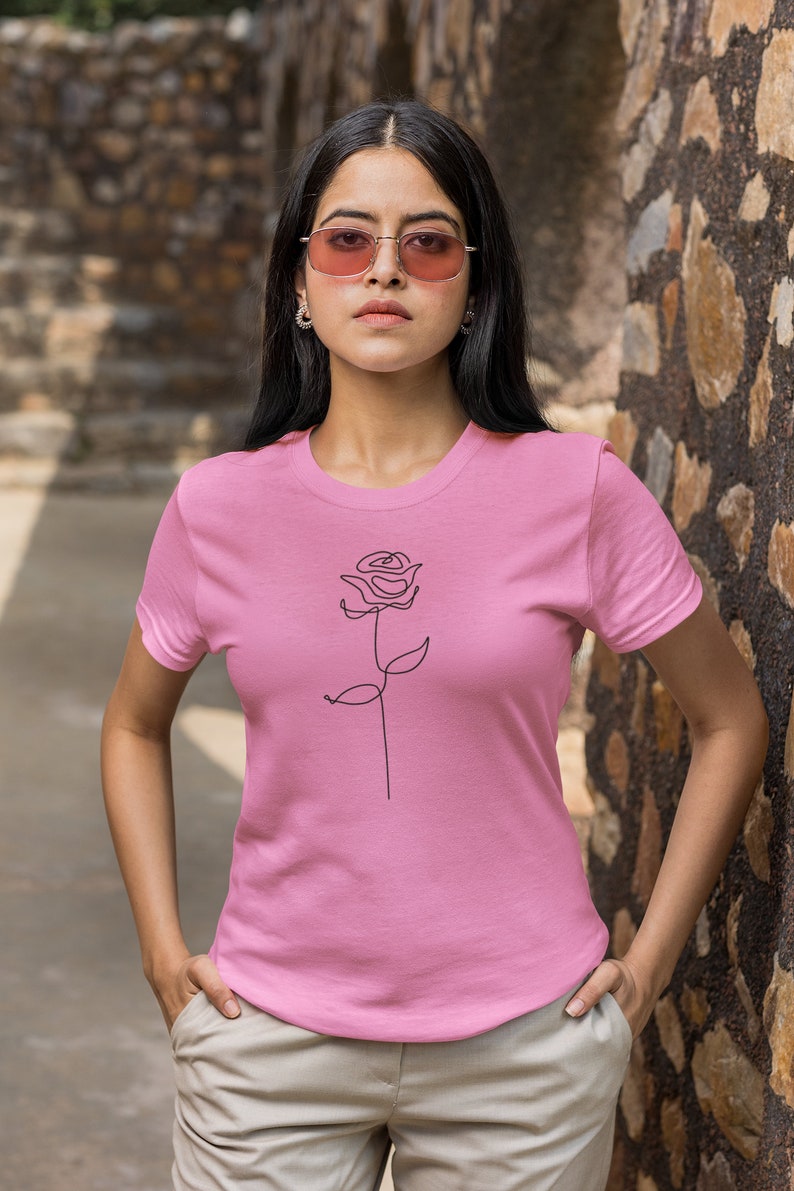 May include: A pink t-shirt with a simple line drawing of a rose on the front.