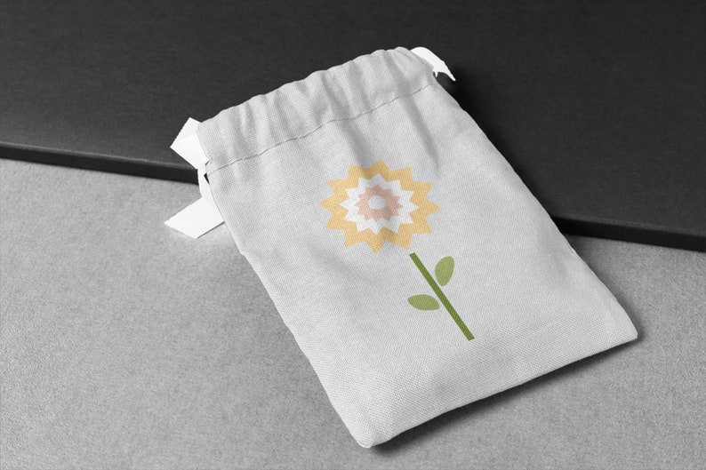 May include: A white drawstring bag featuring a yellow, pink and white flower design. The bag is made from a soft, natural fabric.