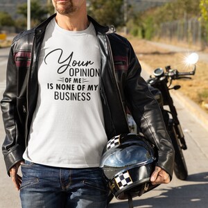 May include: A white t-shirt with the text "Your opinion of me is none of my business" printed on it. The person is wearing a black leather jacket and blue jeans.